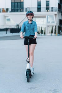 woman wears a helmet while riding electric scooter