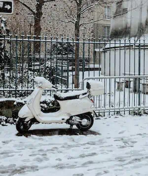 snow falls on parked scooter