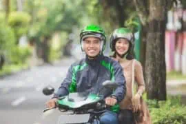 Learn How to Be a Better Motorcycle Passenger with These Tips Motorcycle rider with happy passenger wearing helmet